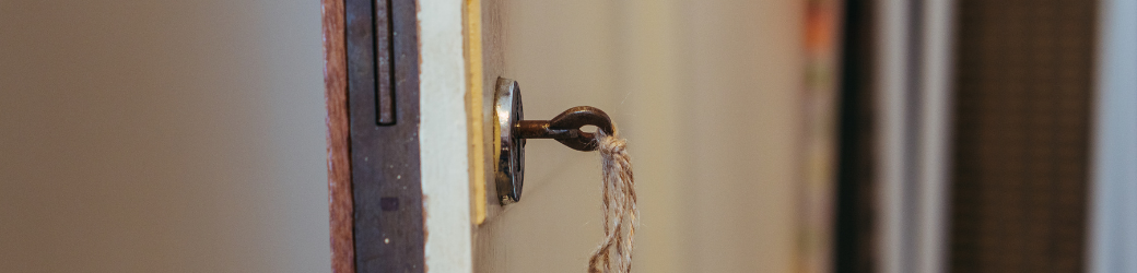 an old fashioned key turning in a lock with door partially open